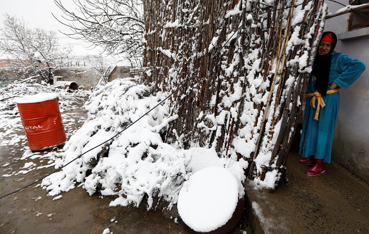 A woman stands outside her house after a snowfall in Wezra, near Medea. (Reuters)