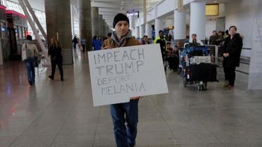 محتج يرفع لافتة تندد بقرار ترامب بشأن حظر السفر ضد مواطني سبع دول في صالة السفر رقم 4 في مطار جون كنيدي في كوينز بنيويورك يوم السبت