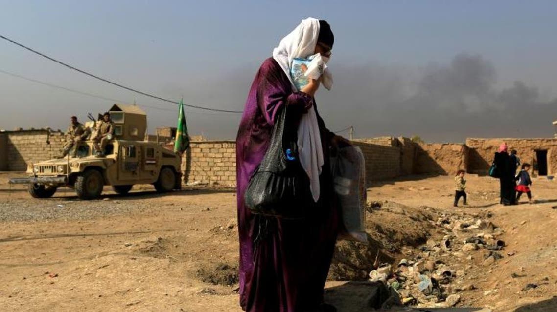 FILE PHOTO: A woman who is fleeing the fighting between Islamic State and the Iraqi army in the Intisar district of eastern Mosul, walks past a military humvee while heading to safer territory in Iraq November 7, 2016. REUTERS/Zohra Bensemra/File Photo