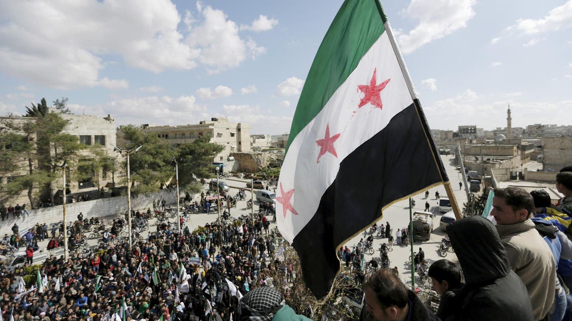 Men carry a Free Syrian Army flag while attending an anti-government protest in Maarat al-Numan, south of Idlib, Syria March 18, 2016. REUTERS/Khalil Ashawi