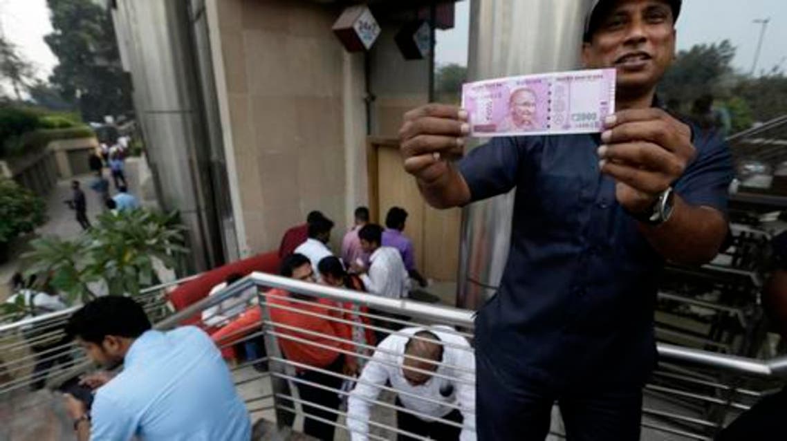 In this Nov. 10, 2016 file photo, a man displays a new Indian currency note of denomination 2000 that he received in exchange for discontinued currency notes outside an Axis Bank branch in central New Delhi, India. (AP)