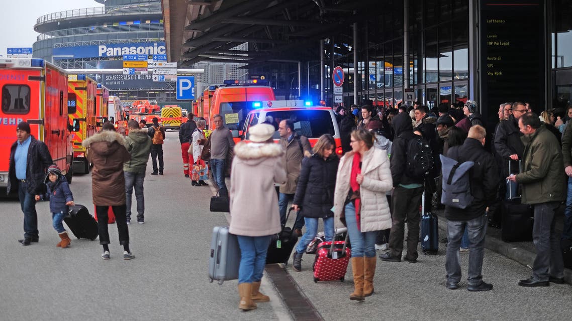 Firefighters with multiple vehicles stand in front of Hamburg airport as passengers leave the terminal on February 12, 2017 in Hamburg, northern Germany, as German emergency services evacuated the airport after people reported an unusual smell as well as respiratory ailments and watering eyes.