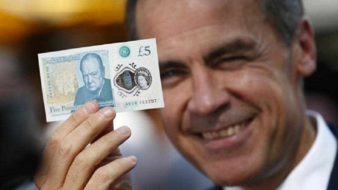 Bank of England governor Mark Carney poses with a new polymer five pound note at Whitecross Street Market in London, Britain September 13, 2016. (Reuters)
