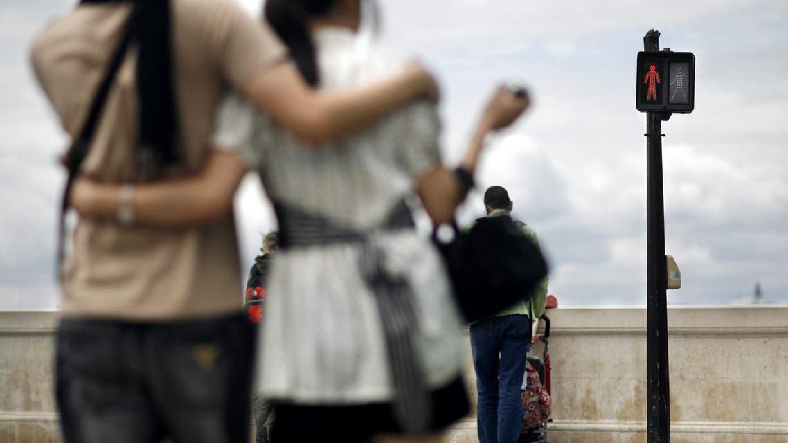 (FILES) This file photo taken on July 11, 2007 shows a couple waiting at a red traffic light in Paris. Culture largely determines how we cross a street, figures in a study published on February 15, 2017 show: Many French do not hesitate to cross a street although the traffic light is red, whereas the Japanese are very unlikely to cross a red light, especially in the presence of other pedestrians. AFP