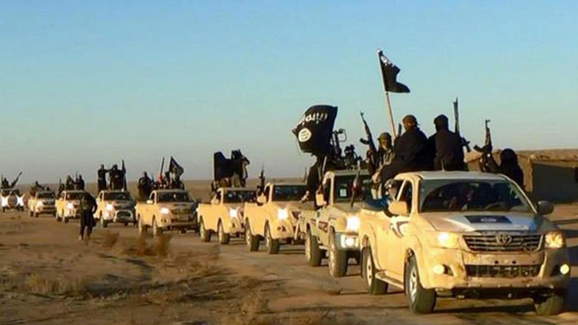 ISIS militants hold up their weapons and wave its flags on their vehicles in a convoy on a road leading to Iraq, in Raqqa, Syria. (Militant photo via AP)
