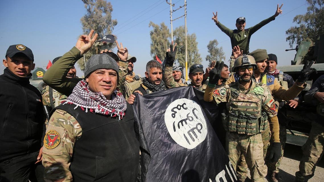 Iraqi forces flash the sign for victory while holding an Islamic State (IS) group flag on February 23, 2017, as they enter Mosul airport on the southern edge of the jihadist stronghold for the first time since the Islamic State group overran the region in 2014. (AFP)
