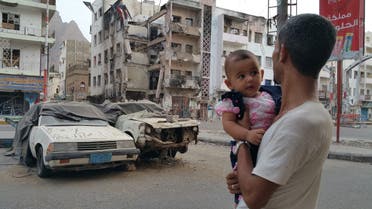 A Yemeni man carrying his daughter looks at a building destroyed during fighting against Houthi fighters in the port city of Aden, Yemen, Sunday, July 19, 2015.  AP