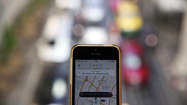 A phone running the Uber application is held above the traffic in central Bangkok December 10, 2014. (Reuters)
