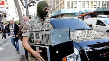 A member of Lebanon's Security Forces confiscates computers as they carry out raids at banking institutions and financial companies in the commercial Hamra district of Beirut as part of an investigation into cash transfers to ISIS on March 8, 2017. (AFP)