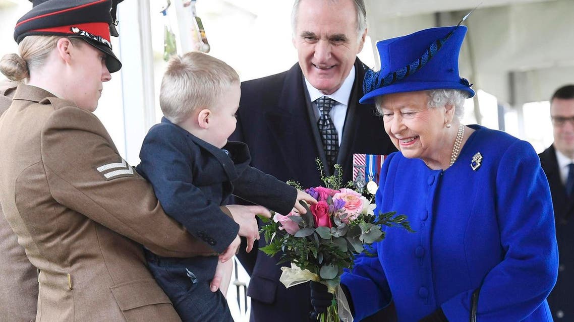 Two-year-old Alfie Lun, 2, is held up by his mother Michelle Lun as he hands a bouquet to Britain's Queen Elizabeth during the the unveiling of a national memorial honouring the Armed Forces and civilians who served their country during the Gulf War and conflicts in Iraq and Afghanistan in London Thursday March 9, 2017. (AP)