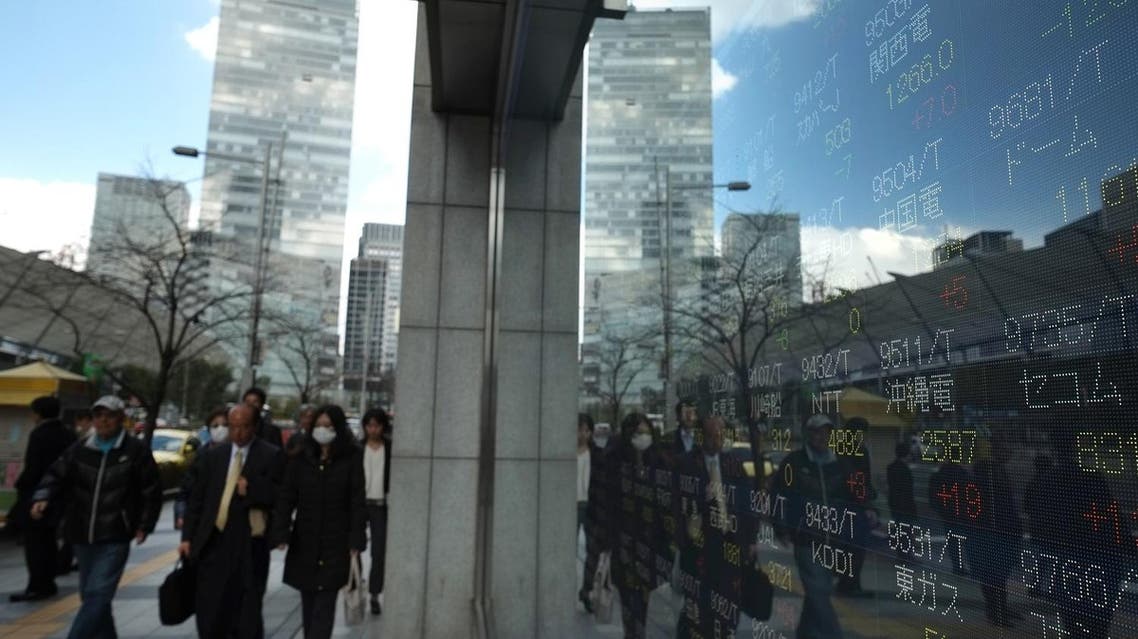 Pedestrians walk next to an electric quotation board flashing the Nikkei key index of the Tokyo Stock Exchange (TSE) in front of a securities company in Tokyo on March 10, 2017. (AFP)
