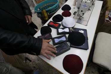 A Palestinian man shows bow ties and skull caps, also known as kippot or yarmulke for Jewish worshippers, at a sewing factory in Gaza City March 11, 2017. Picture taken March 11, 2017. (Reuters)