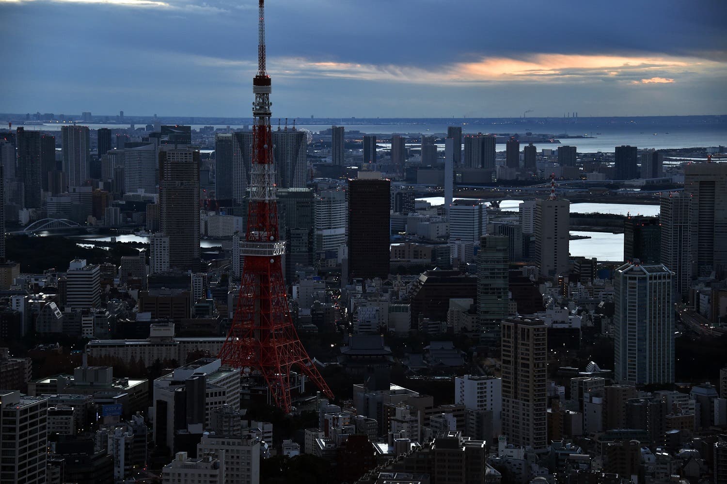 Clouds obscure the sun rise as people come out to see dawn bring in the new year over Tokyo Tower (L) and the city's skyline on New Year's Day on January 1, 2015. Millions of Japanese people visit shrines and temples to pray for the well-being of their families at the New Year. AFP