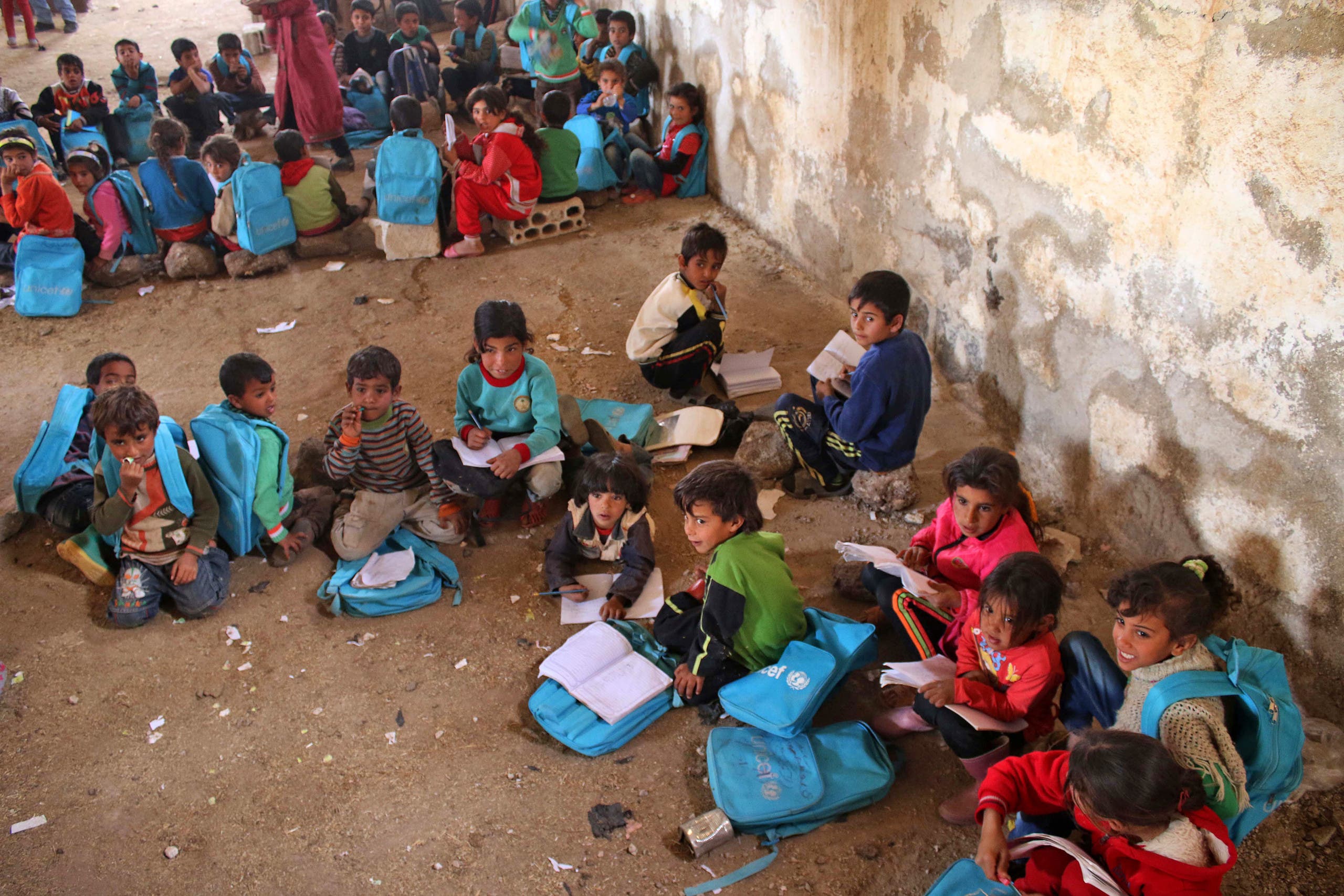 Syrian children sit during class a barn that has been converted into a makeshift school to teach internally displaced children from areas under government control, in a rebel-held area of Daraa, in southern Syria on November 10, 2016