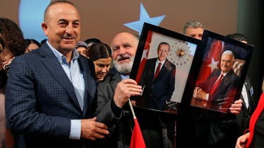 Turkish Foreign Minister Mevlut Cavusoglu poses with a supporter holding portraits of Turkish President Recep Tayyip Erdogan and Prime Minister Binali Yildirim (R) at the end of a political rally on Turkey's upcoming referendum, in Metz, France, March 12, 2017