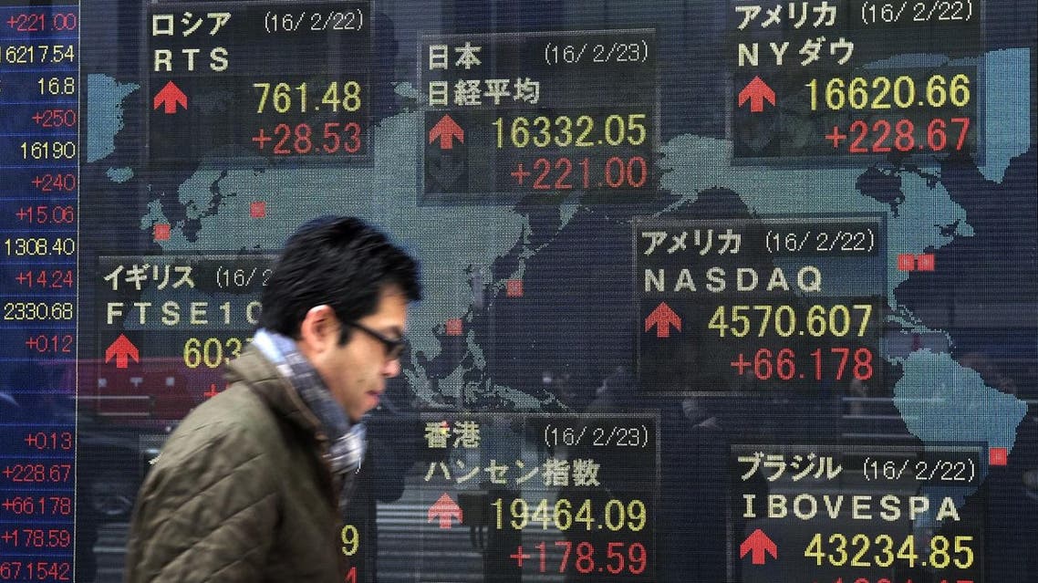 A pedestrian walks past an electric quotation board showing share price indexes of the Tokyo Stock Exchange (C, top) in front of a securities company in Tokyo. (AFP)