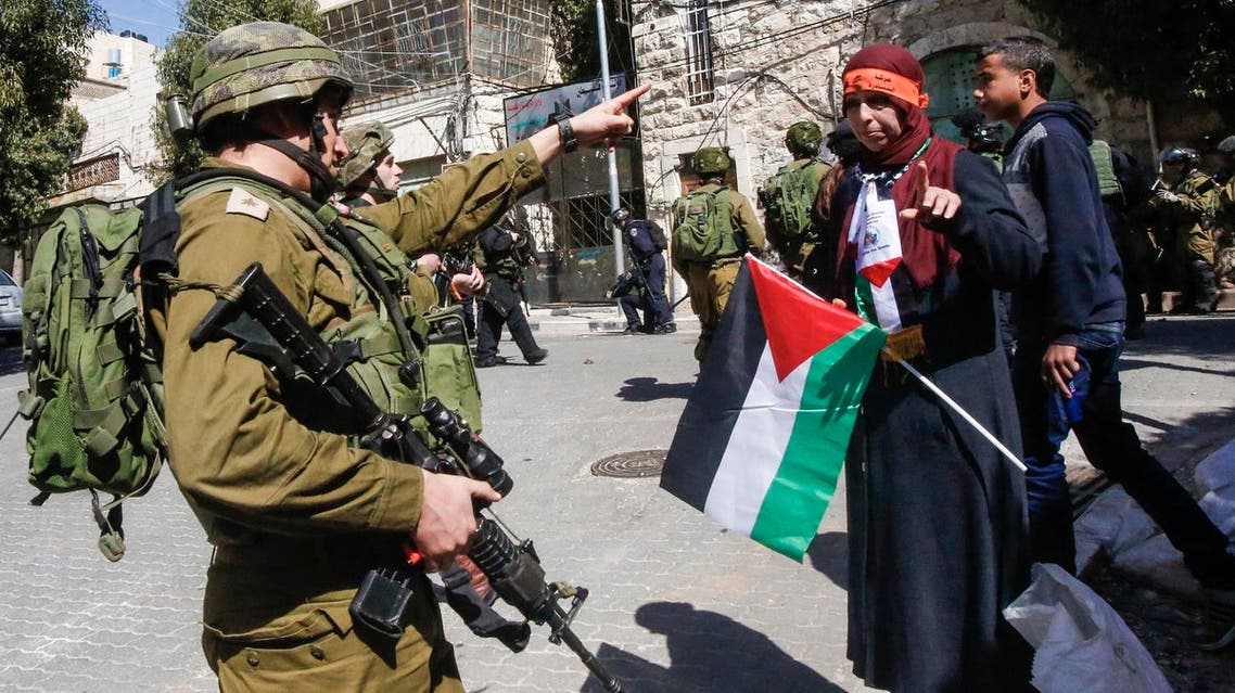 An Israeli soldier points at a woman carrying a Palestinian flag during a protest calling for the opening of Shuhada Street, which is largely closed off to Palestinians, near a Jewish settler enclave in the heart of the West Bank city of Hebron, coinciding with the anniversary of a 1994 massacre carried out by a far-right Jewish settler, on February 24, 2017. AFP