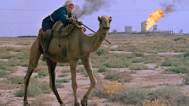 A man rides a camel while unwanted gas byproducts are burned off at a petrochemical factory in the background in the desert near Ahwaz, Iran, July 1971. (AP)