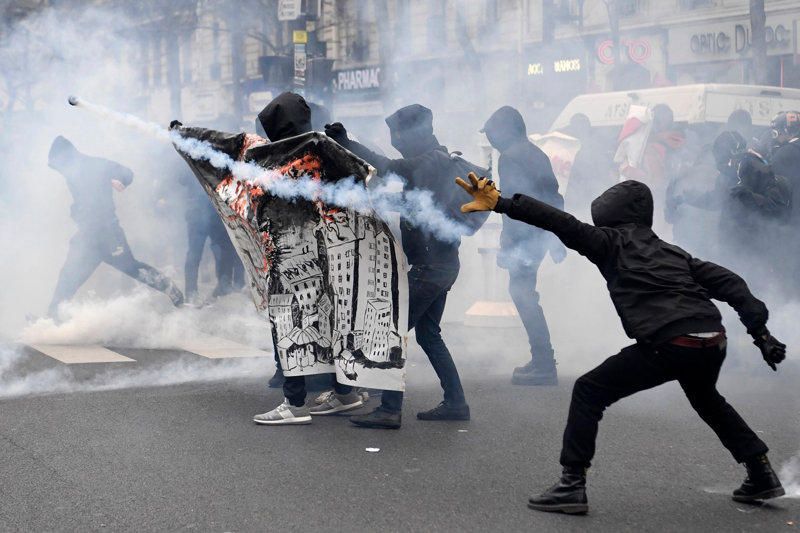Hooded participants throw back tear gas canisters as they clash with police within a demonstration called by the families of the victims of alleged police brutality, AFP