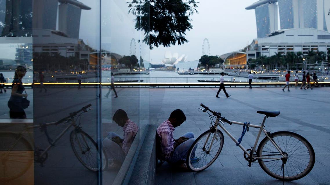 A migrant worker checks his mobile phone at the Marina Bay Promenade in the central business district of Singapore. (File Photo: Reuters)
