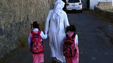 Saudi man Yazid al-Fefi holds the hands of his daughters as they arrive to their school after making their way through Fifa Mountain, in Jazan, south of Saudi Arabia, December 15, 2016. reuters