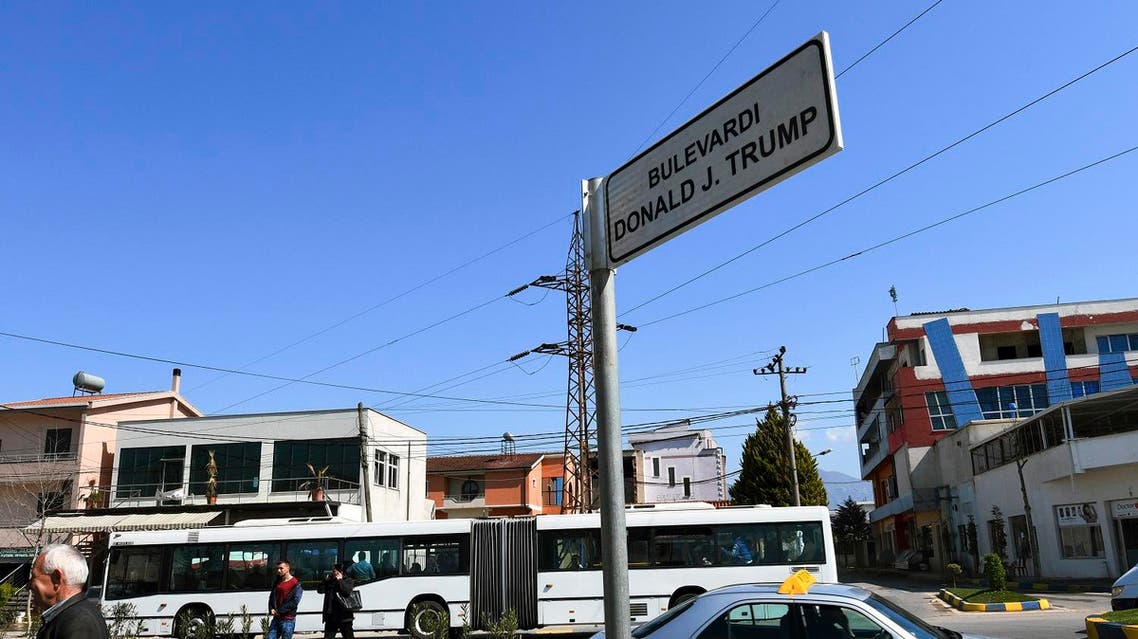 This picture taken on March 21, 2017, shows people walking by a street sign reading "Donald J. Trump" boulevard in the city of Kamza. The boulevard was named after US President Donald Trump, in the small suburban town of Kamza, some 15 km from the capital Tirana. The mayor of Kamza, a developing town whose population and surface has increased from rapid internal migration, has given the names of world capitals and famous personalities to the new streets of his municipality. AFP