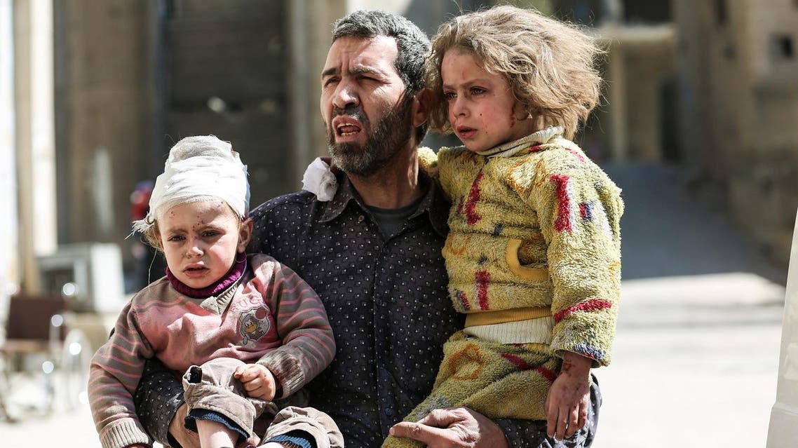 A Syrian man carries two injured children after a reported air strike in the rebel-controlled town of Hamouria, in the eastern Ghouta region on the outskirts of the capital Damascus, on March 25, 2017. AFP