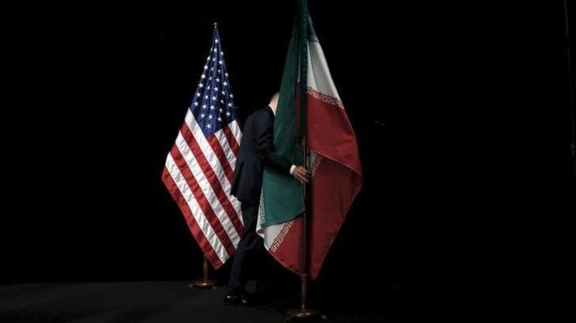  A staff member removes the Iranian flag from the stage during the Iran nuclear talks in Vienna, Austria July 14, 2015. REUTERS/Carlos Barria