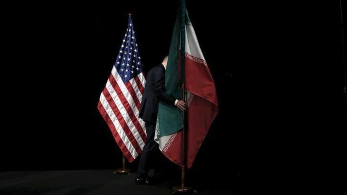 A staff member removes the Iranian flag from the stage during the Iran nuclear talks in Vienna, Austria July 14, 2015. REUTERS/Carlos Barria