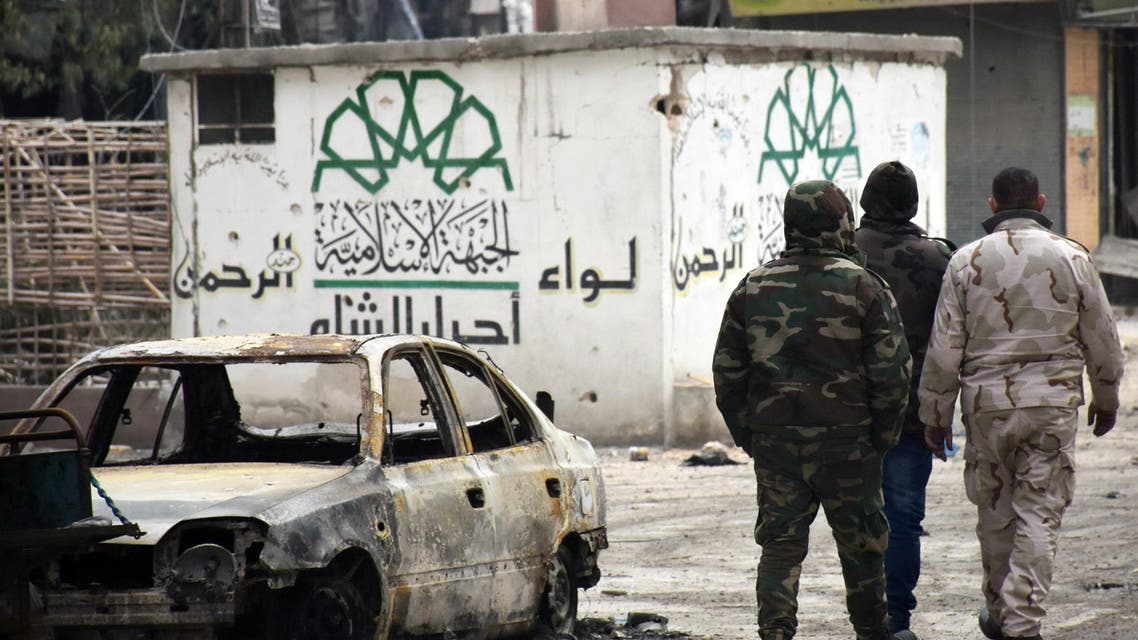 Syrian government forces walk past a destroyed vehicle and a graffiti bearing the emblem of the Ahrar Al-Sham's Rahman Brigade of the Islamic Front (L) in the former rebel-held Sukkari district in the northern city of Aleppo on December 23, 2016 after Syrian government forces retook control of the whole embattled city. Syrian troops cemented their hold on Aleppo after retaking full control of the city, as residents anxious to return to their homes moved through its ruined streets. (AFP)