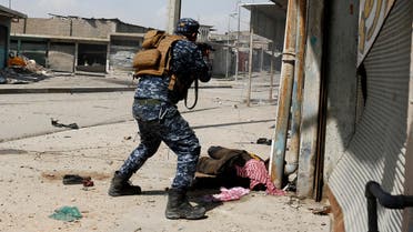 ATTENTION EDITORS - VISUAL COVERAGE OF SCENES OF INJURY OR DEATH Federal police member fires his rifle near the body of an Islamic State fighter during a battle at Jada district in western Mosul, Iraq March 29, 2017. REUTERS/Youssef Boudlal TEMPLATE OUT