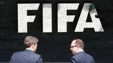 Two men talk to each other in front of the FIFA logo at the FIFA headquarters in Zurich, Switzerland, Wednesday, May 27, 2015. (AP)