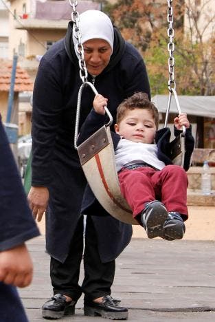 Hajar Saleh pushes her grandson Jaafar on a swing at a garden in the Damascus district of Mezzeh, Syria March 30, 2017. REUTERS/Omar Sanadiki