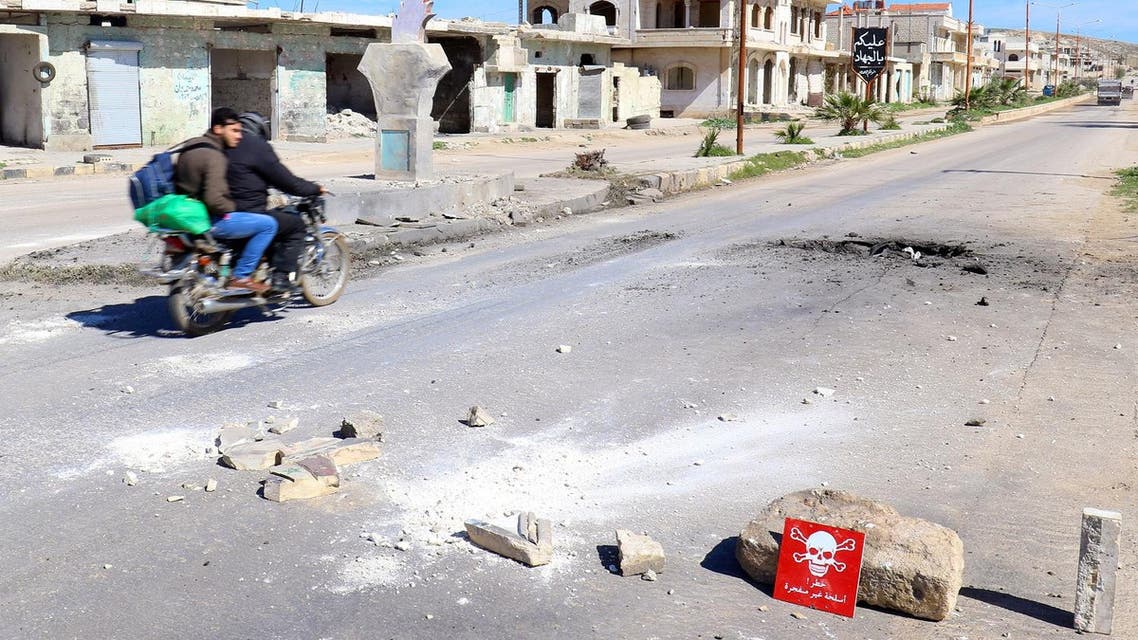 Men ride a motorbike past a hazard sign at a site hit by an airstrike on Tuesday in the town of Khan Sheikhoun in rebel-held Idlib, Syria April 5, 2017. The hazard sign reads, “Danger, unexploded ammunition” (File Photo: Reuters/Ammar Abdullah)