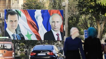 A picture taken on March 9, 2017 in the northern Syrian city of Aleppo, which was recaptured by government forces in December 2016, shows Syrians walking past a giant poster of Syrian President Bashar al-Assad (L) and his Russian counterpart Vladimir Putin (R). JOSEPH EID / AFP