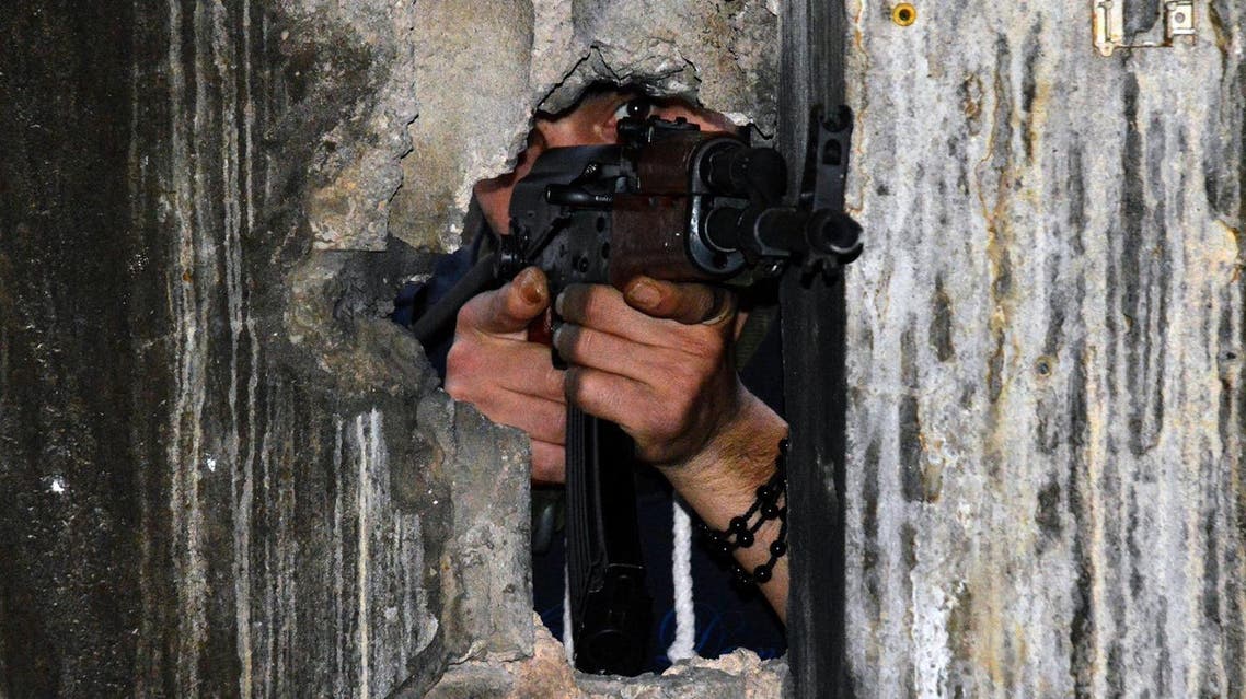 A member of the joint Palestinian security takes position through a hole in a wall with a kalashnikov assault rifle in Ain al-Hilweh camp, Lebanon's largest Palestinian refugee camp, near the southern coastal city of Sidon, on April 12, 2017, after clashes that took place earlier in the week between an extremist group and the security force. Fighting erupted on April 7, 2017 after Palestinian factions deployed throughout the camp as part of a joint security force aimed at combatting the influence of a local Islamic extremist group. (AFP)