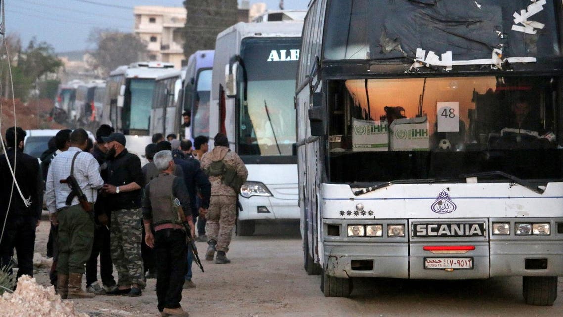Syrian rebel fighters stand guard as buses bringing a new batch of evacuees from Waer, the last opposition-held district of Syria's third city Homs, arrive in the city of al-Bab in the northern Aleppo province at sunset on April 18, 2017. (AFP)
