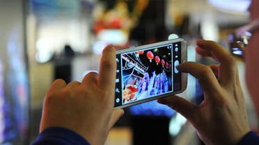 A traveler uses a smartphone to capture a themed interactive digital display at an airport. (Shutterstock)