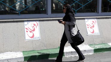 An Iranian woman walks past election posters of President Hassan Rowhani, who is running for the presidential elections, in Tehran on April 23, 2017. (AFP)