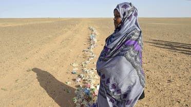 Zghala, a Saharawi woman, stands in front of fake flowers looking at Moroccan soldiers in the Al-Mahbes area as she accompanies her 14-year-old son to show him the wall separating the Polisario controlled Western Sahara from Morocco on February 3, 2017. (File Photo: AFP)