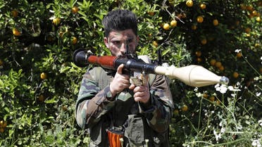 A Hezbollah fighter is seen standing at attention in an orange field near the town of Naqura on the Lebanese-Israeli border on April 20, 2017. (AFP)