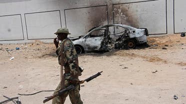 A Somali soldier walks near the wreckage of a car bomb blast near Aden Abdule international airport in Mogadishu on April, 16, 2017. (AP)