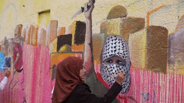 A Palestinian woman paints a mural, depicting a masked Palestinian holding a knife, in support of Palestinians committing stabbing attacks against Israelis, in Rafah in the southern Gaza Strip November 3, 2015. (Reuters)