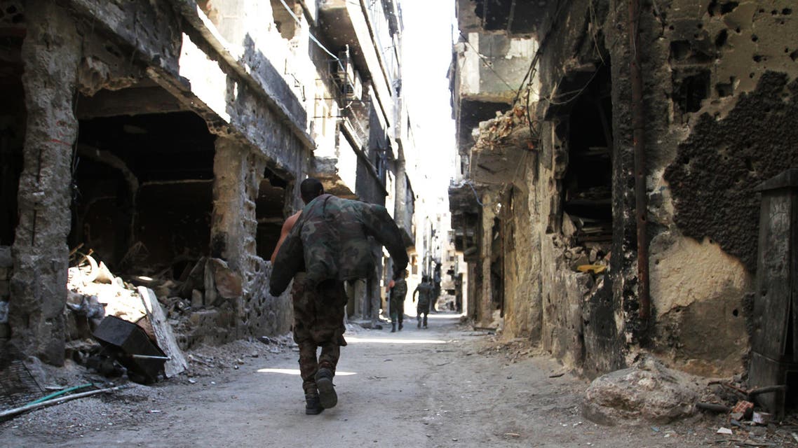 Men walk past destroyed buildings in the Yarmuk Palestinian refugee camp in the Syrian capital Damascus on April 6, 2015. Around 2,000 people have been evacuated from the camp after the Islamic State group seized large parts of it. At least 26 people, including civilians as well as fighters from IS and Palestinian factions, had been killed in the camp according to the Syrian Observatory for Human Rights. A