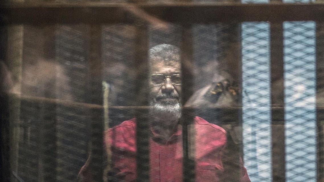Egypt's ousted Islamist president Mohamed Morsi, wearing a red uniform, stands behind the bars during his trial in Cairo at the police academy in Cairo on April 23, 2016. An Egyptian court postponed its verdict and sentence in the trial of ousted Islamist president Mohamed Morsi, who is charged with spying for Qatar. AFP