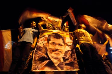 Members of the Muslim Brotherhood and supporters of deposed Egyptian President Mohamed Mursi hold a banner with his picture, in Cairo July 12, 2013. (Reuters)