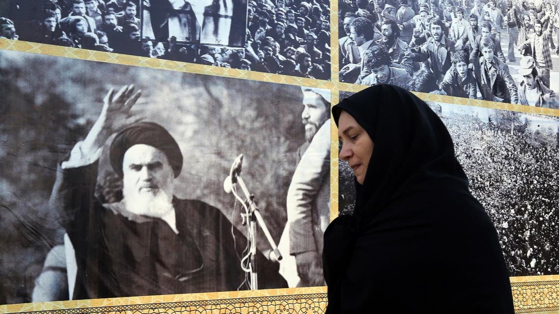 An Iranian woman walks past a giant board displaying pictures of Ayatollah Ruhollah Khomeini in southern Tehran on February 1, 2016. (AFP)