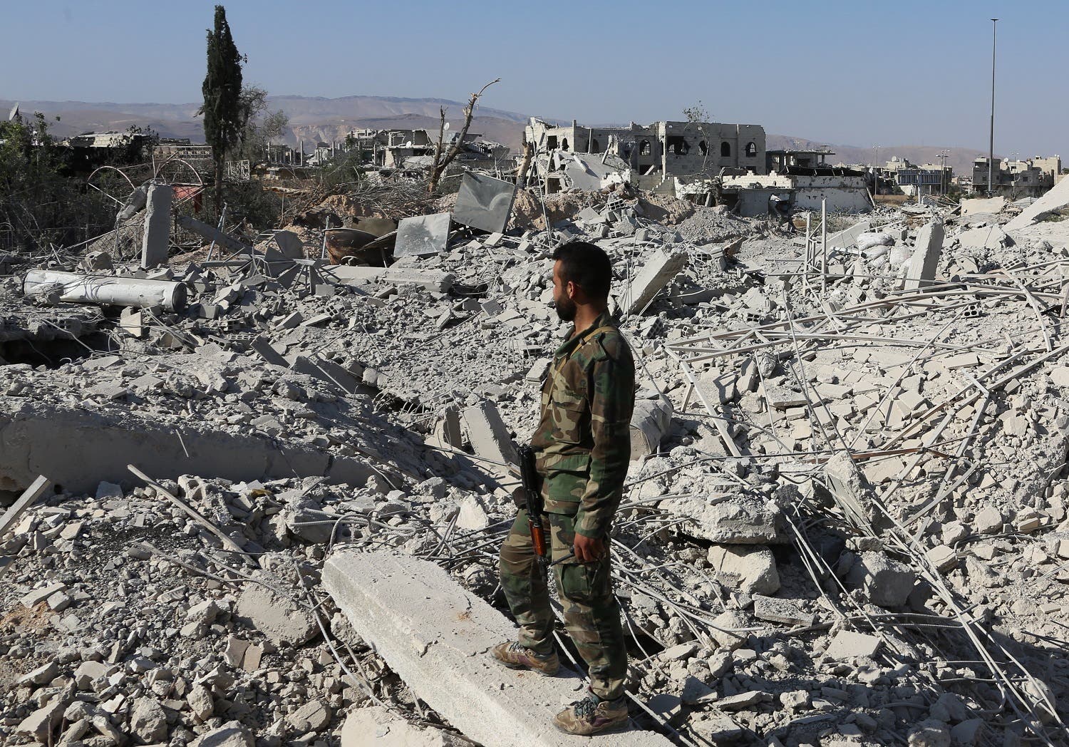 A member of the Syrian pro-government forces stands on the rubble of destroyed buildings as troops advance through Qabun district, on the outskirts of the capital Damascus, on May 13, 2017, during an offensive to retake the area from opposition fighters. (AFP)