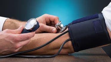 Cropped image of male doctor checking blood pressure of patient at table. (Shutterstock)