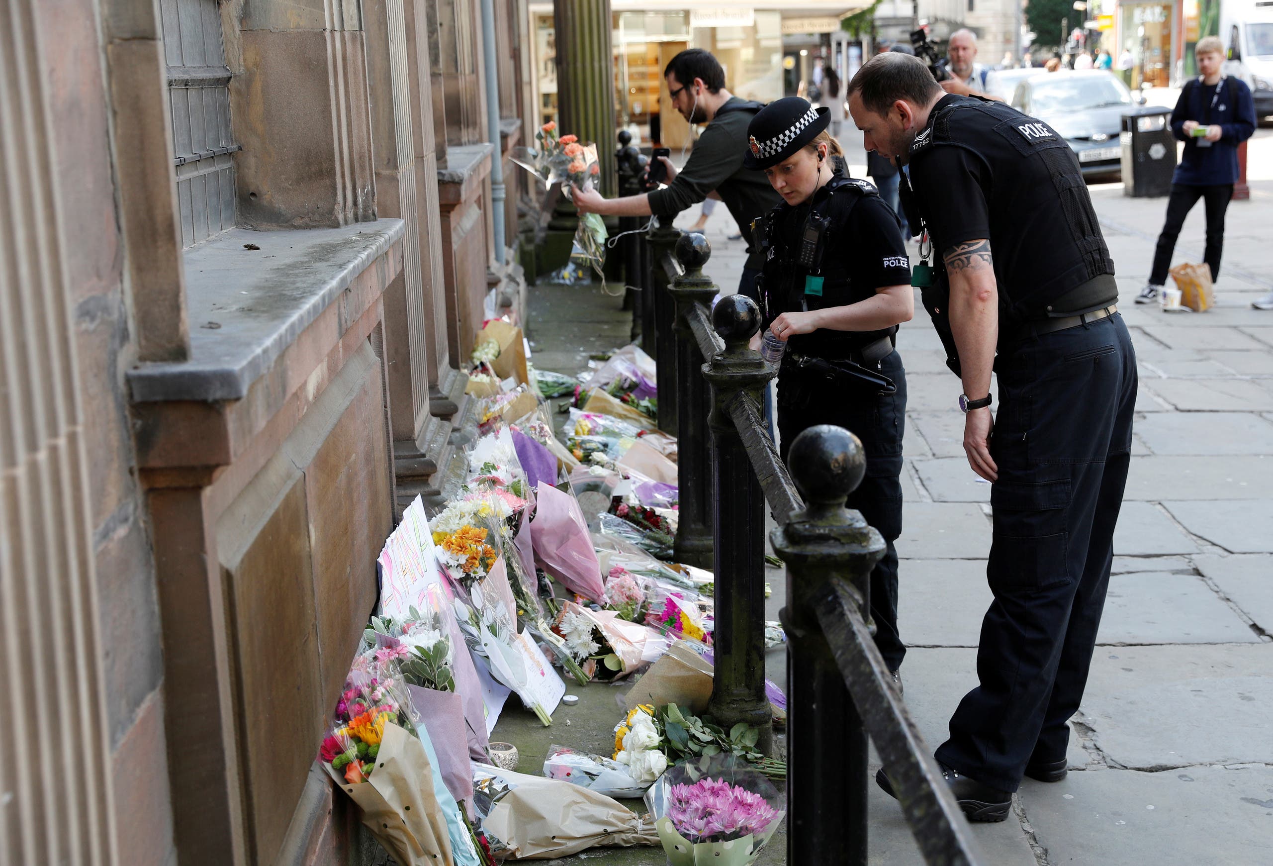 Police officers look at flowers and messages in central Manchester. (Reuters)